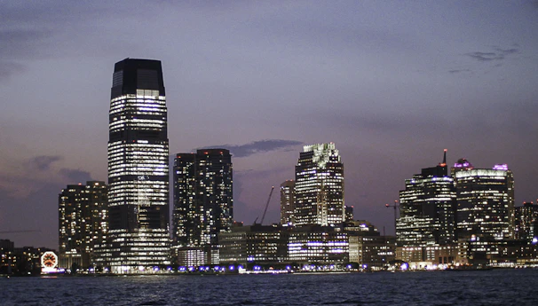 High-resolution photo of a modern city skyline with glowing lights against a twilight sky.
