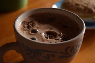 Close-up of a hot chocolate bomb melting in a steaming mug, releasing swirls of chocolate and marshmallows.
