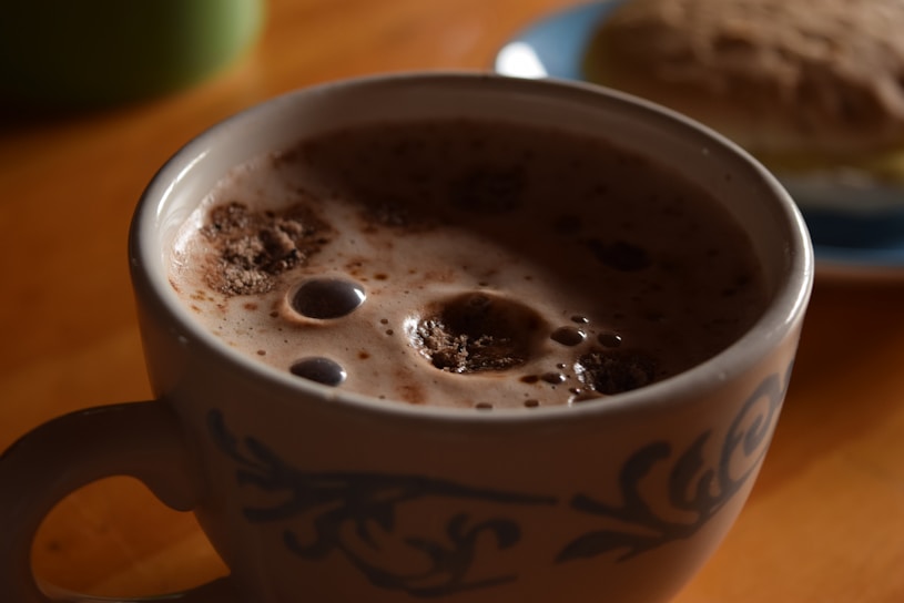 Close-up of a hot chocolate bomb melting in a steaming mug, releasing swirls of chocolate and marshmallows.
