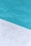 A close-up view of a pool with clear blue water and a corner of light gray stone or concrete coping. The contrast between the water and the poolside creates a clean, refreshing look.