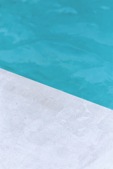Close-up of a high-quality pool water pump installed beside a sparkling blue pool under sunlight.