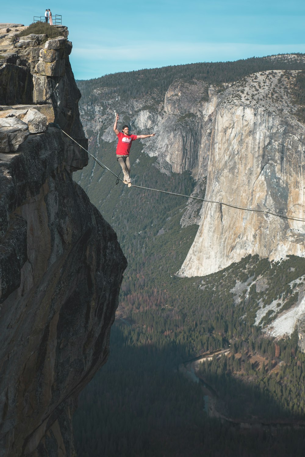 person standing on rope near mountain cliff