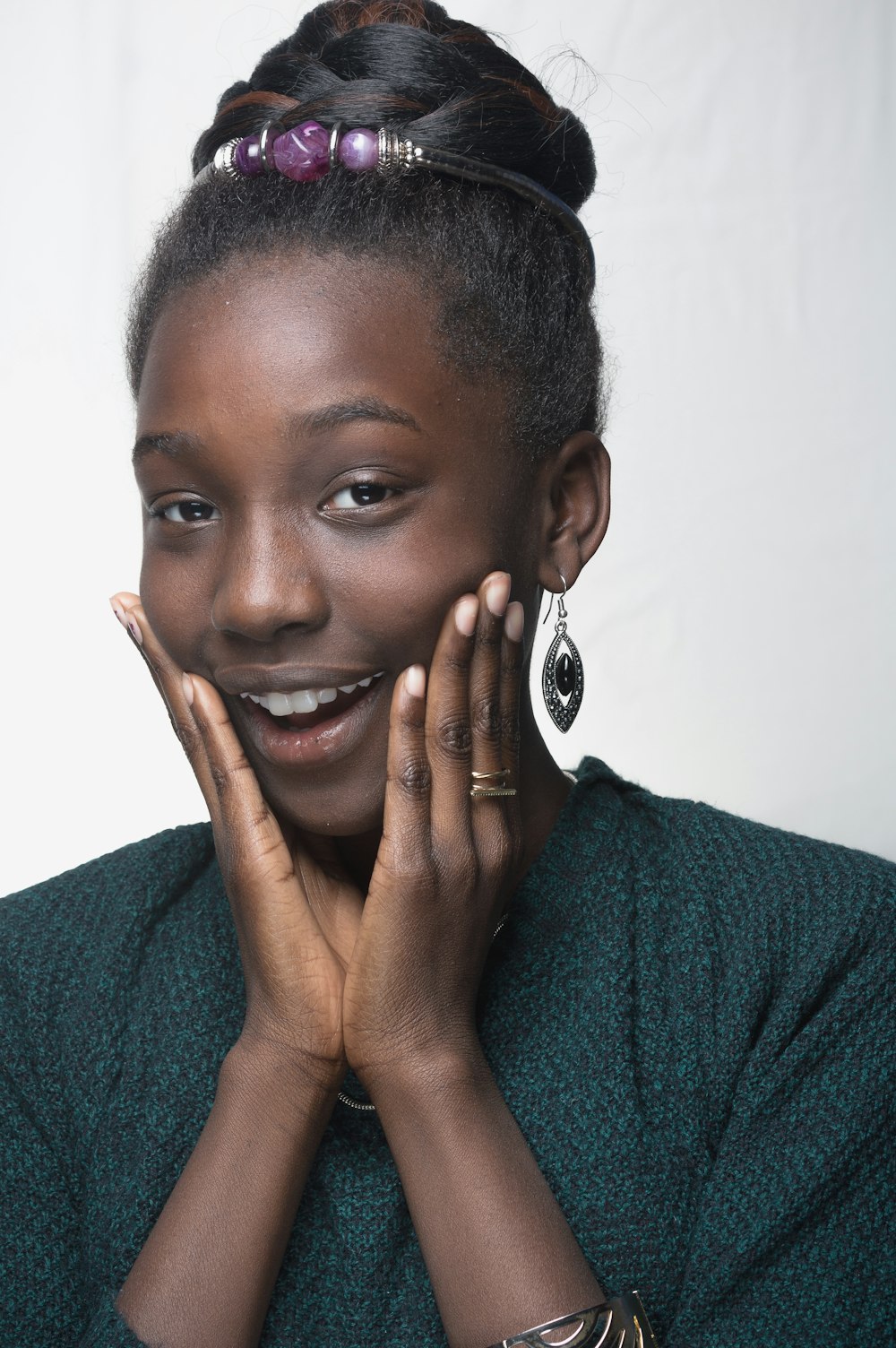 woman wearing teal shirt with hands on face