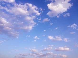 Clear blue sky with scattered fluffy clouds above Tripura’s countryside.