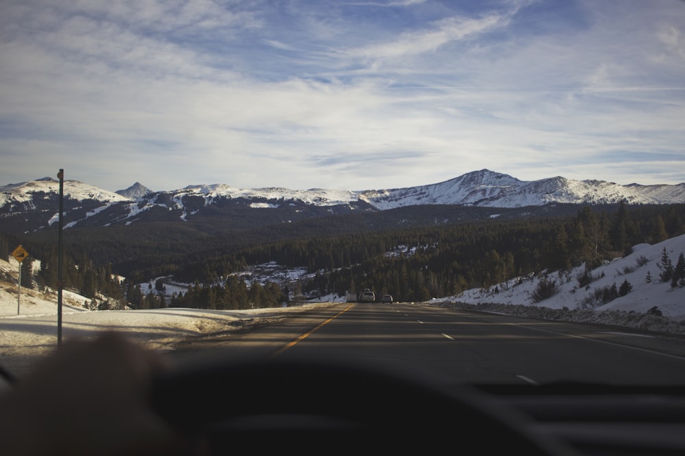 gray concrete road overviewing snow caped mountain