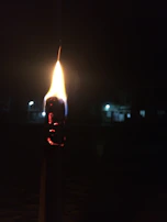 A close-up of a torch symbol glowing softly on a dark fabric, highlighting texture and depth.