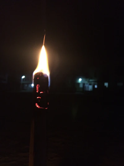 Close-up of a delicate, glowing candle with a flickering flame in a dark setting
