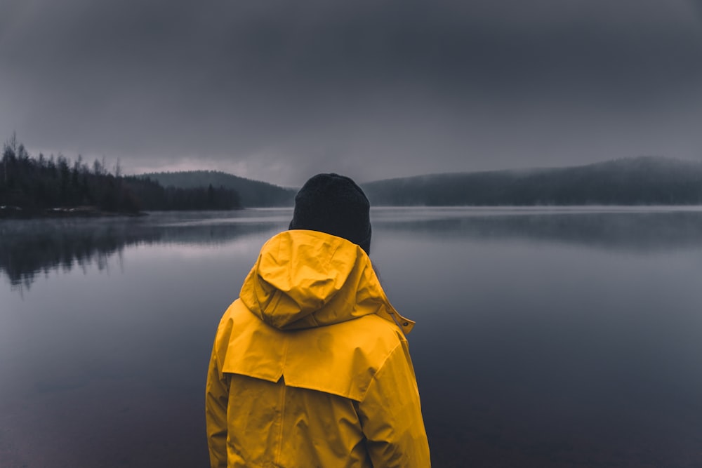 man facing calm body of water under cloudy sky