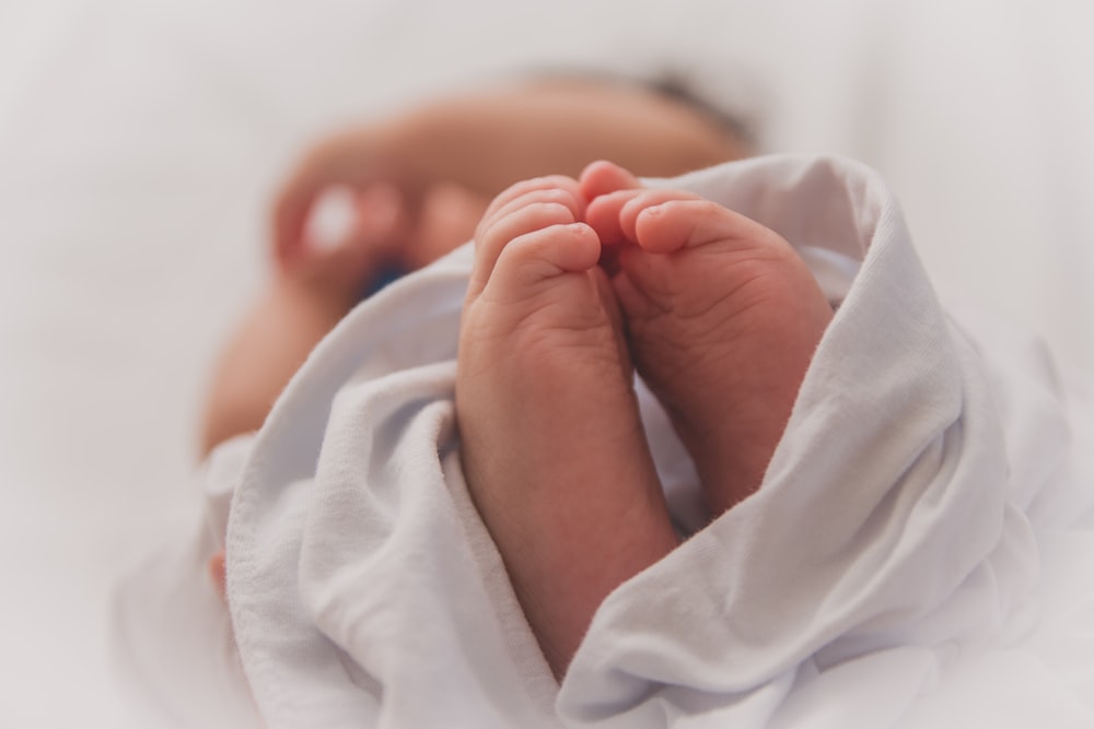 bébé recouvert d’une couverture blanche