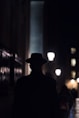 man in black hat walking on sidewalk during night time