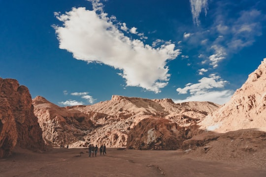 group of people standing between mountains during day time in Valle de la Luna Chile