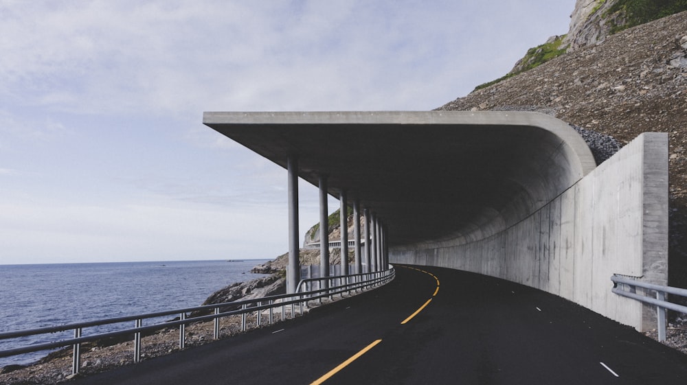 white road tunnel beside sea