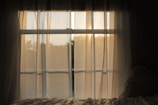 Soft sunlight filters through sheer white curtains, casting a gentle gold glow over a minimalist meditation space.