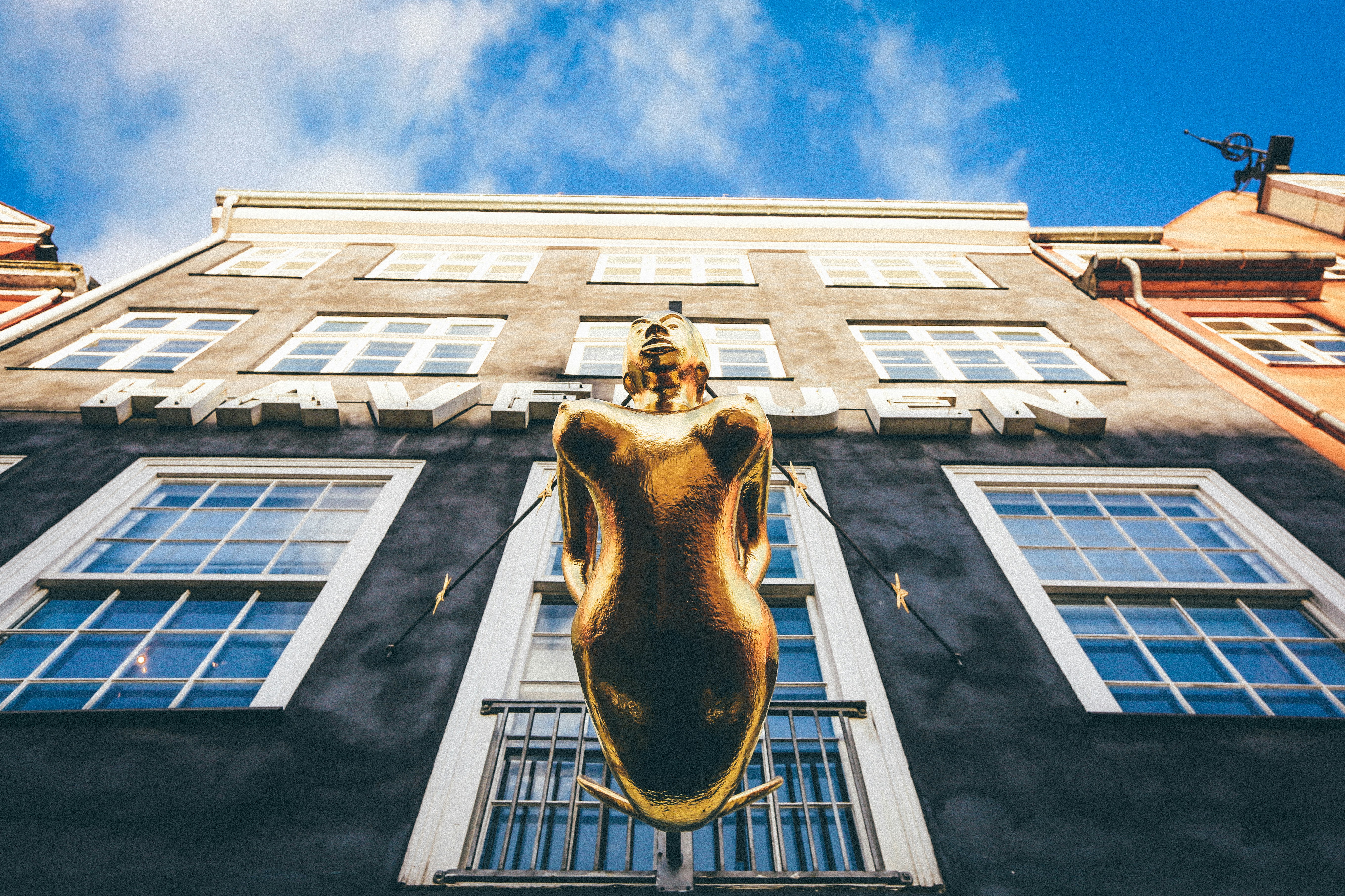 low angle photography of brown woman statue in front of building under white and blue building