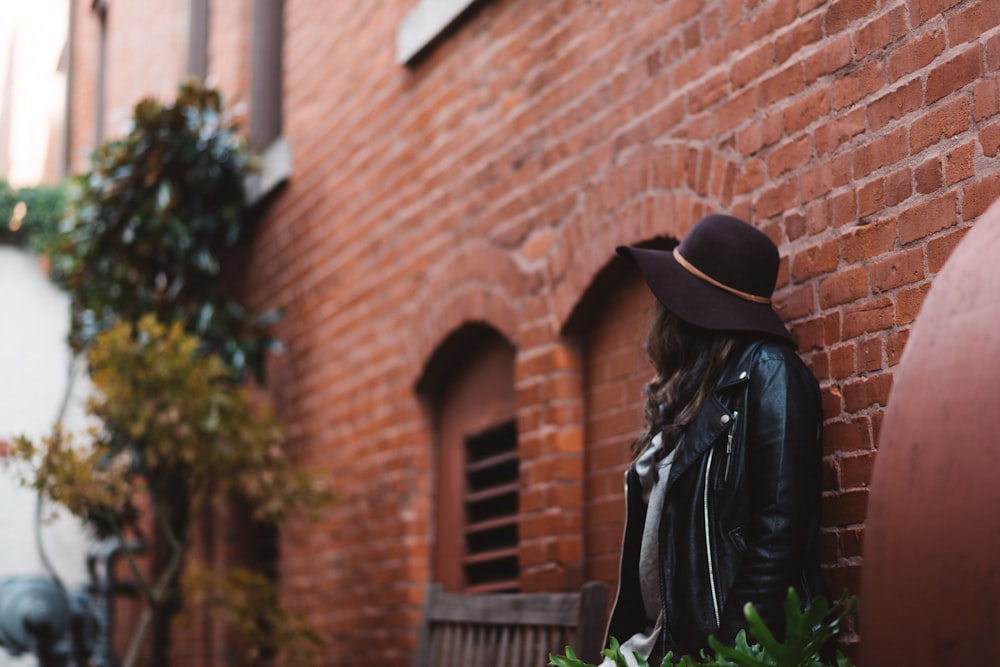 woman leaning against wall during daytime