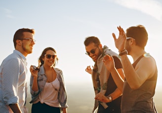 three men and one woman laughing during daytime