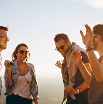 three men and one woman laughing during daytime