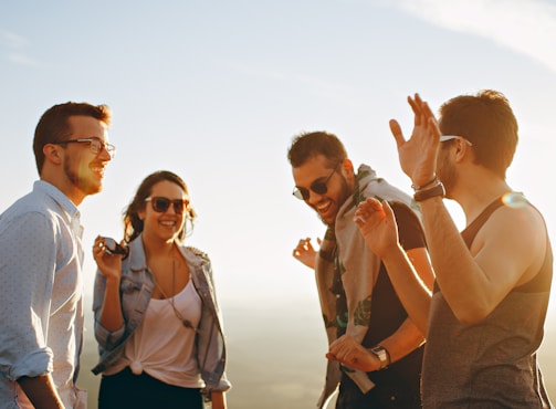 three men and one woman laughing during daytime