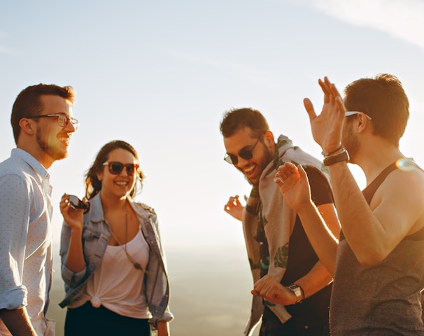 three men and one woman laughing during daytime