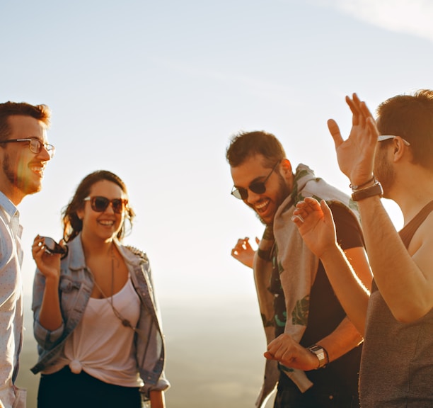 three men and one woman laughing during daytime