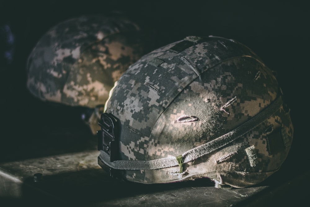 gray and brown camouflage nutshell helmet on table