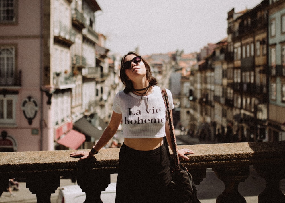 woman leaning back against the concrete hand rail surrounded by buildings