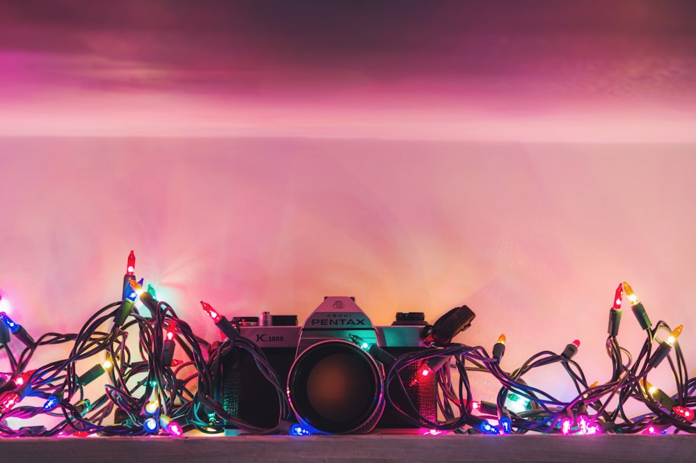 black and silver Pentax range finder camera surrounded by string lights