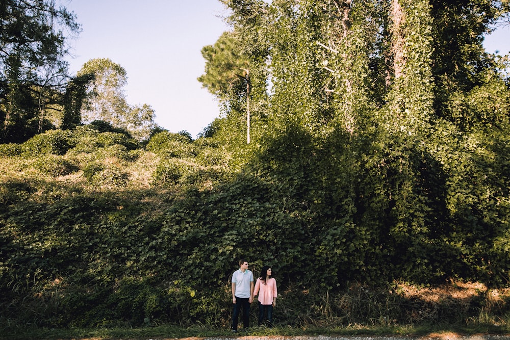 woman and man holding hands in front of tree