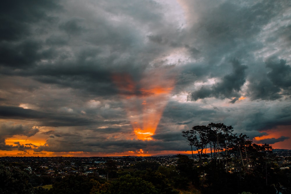 the sun is setting over a city and trees