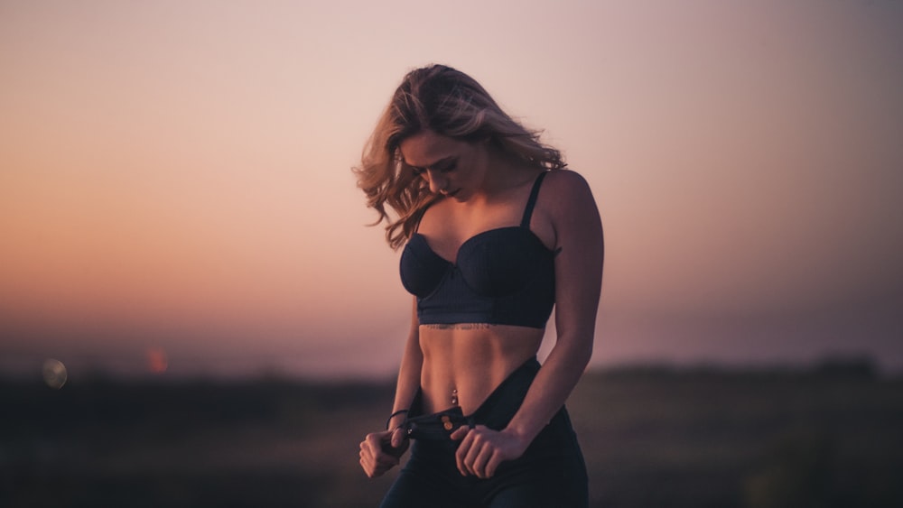 mulher em pé no campo durante o pôr do sol