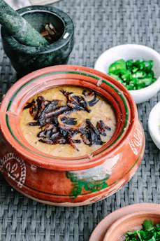 A rustic clay pot filled with golden Bilona ghee beside fresh cow milk and churn.