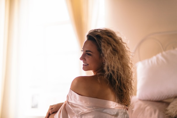 A VIP call girl relaxing elegantly on a plush hotel bed with soft lighting.