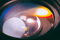 Close-up of a camera lens reflecting colorful studio lights.