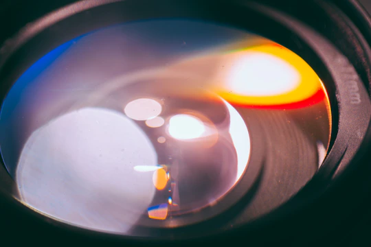 Close-up of a finely polished optical lens reflecting blue light.