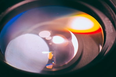 A close-up of a camera lens reflecting colorful anime scenes.