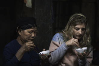 two women using chopsticks for eating