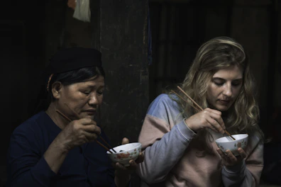 two women using chopsticks for eating