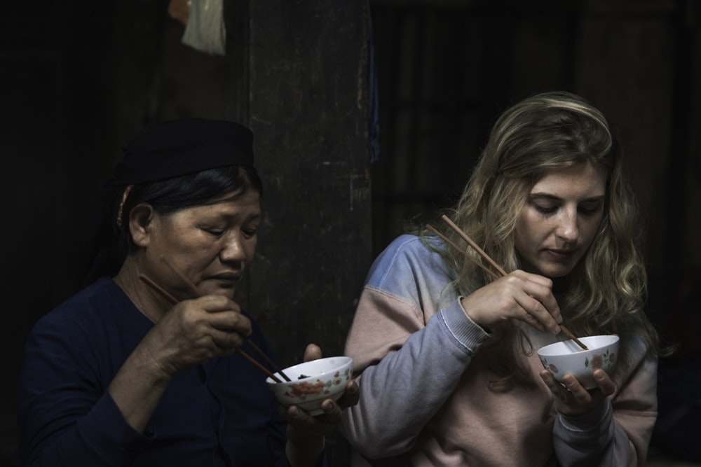 two women using chopsticks for eating