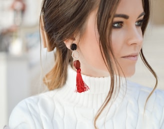 focus photography of woman wearing red tassel earrings while looking on her left side