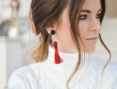 focus photography of woman wearing red tassel earrings while looking on her left side