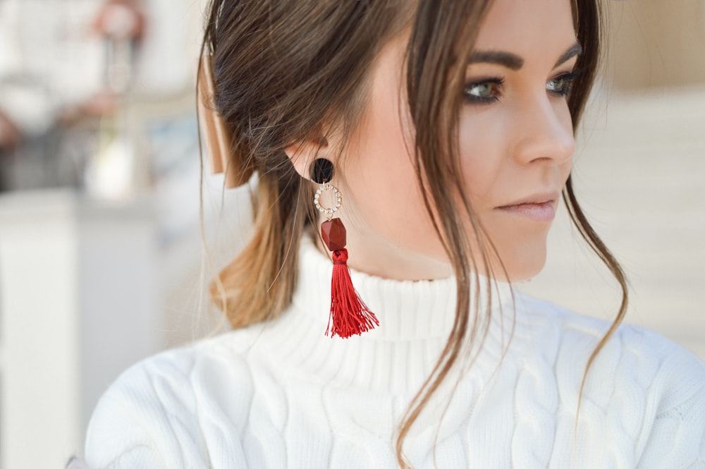 focus photography of woman wearing red tassel earrings while looking on her left side