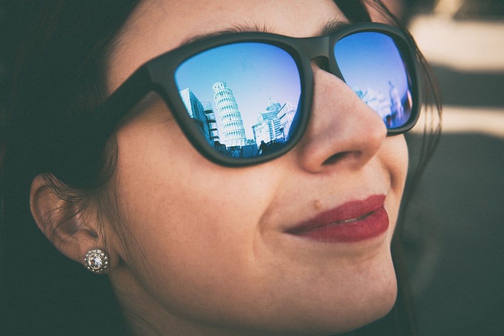 closeup photography of woman wearing black Wayfarer-styled blue lens sunglasses