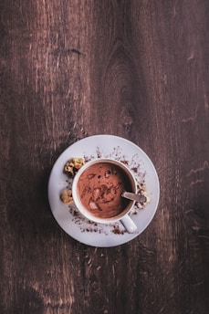 A cozy scene showing a cup of hot chocolate next to Swedish chocolate pieces on a wooden table.