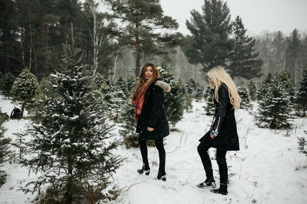 two woman walking towards snow