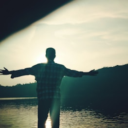 Serene outdoor scene with a person stretching by a calm lake at sunrise.