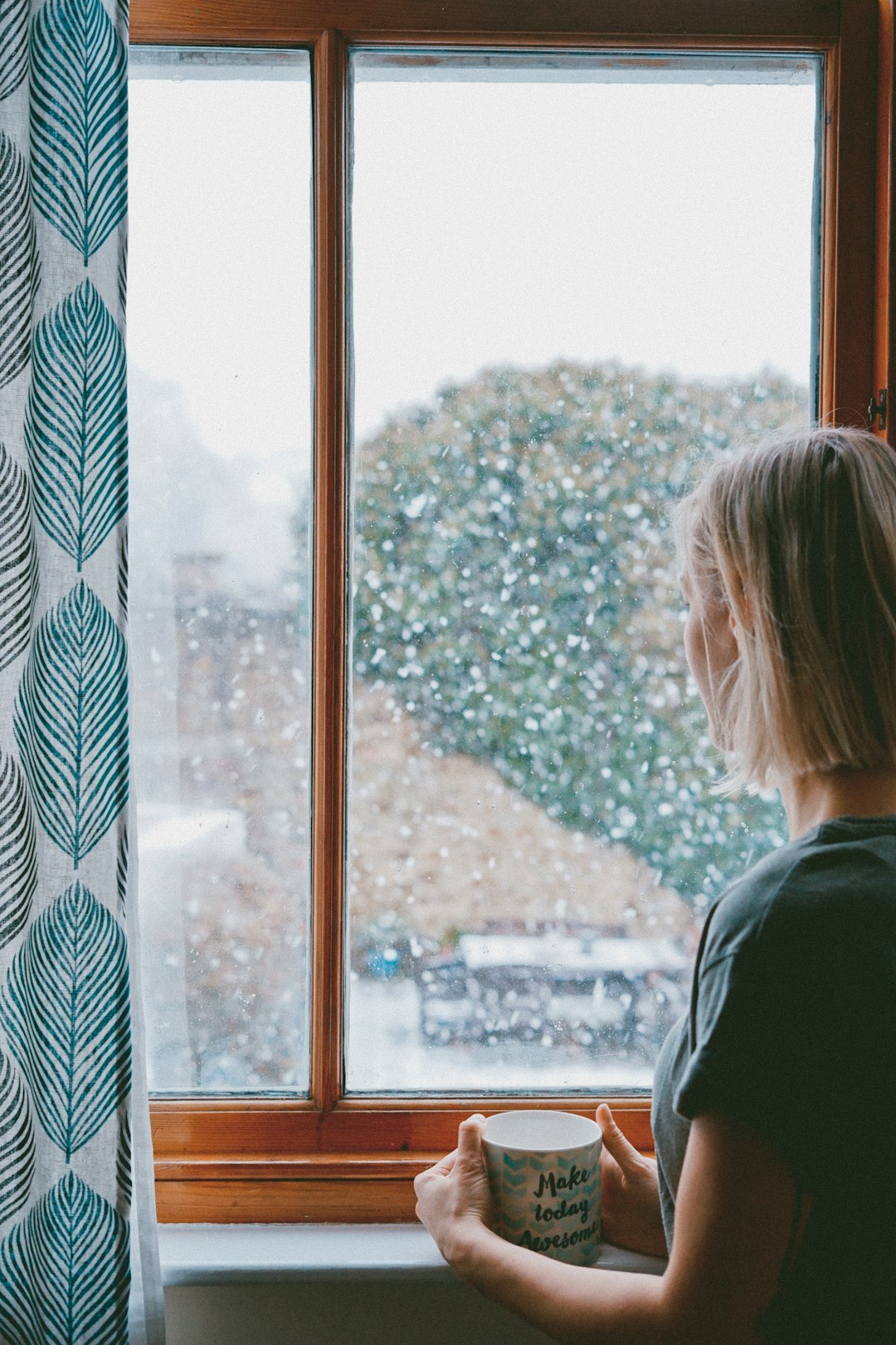 Woman staring out the window covered in rain droplets.