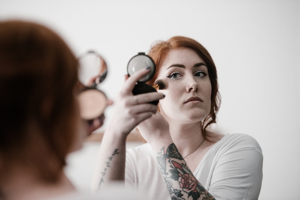 Selektive Fokusfotografie einer Frau, die Rouge auf ihr Gesicht aufträgt