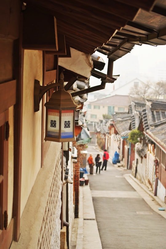 three person standing between houses in Bukchon Hanok Village South Korea