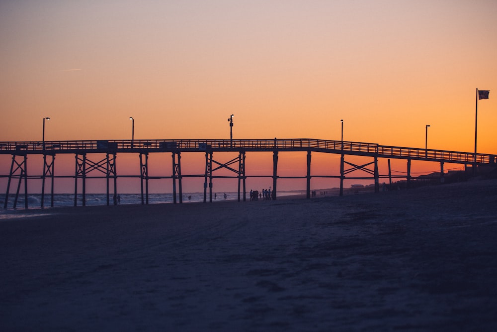 silhouette of dock near body of water under golden hour