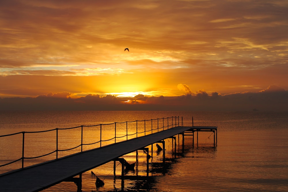 dock on body of water during sunset